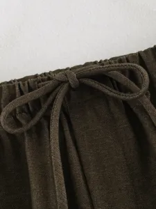 Dark brown pants waist detail, elastic drawstring waistband, fine fabric texture close-up.