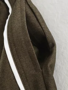 Close-up detail shot of the brown jacket collar featuring contrasting white piping trim.