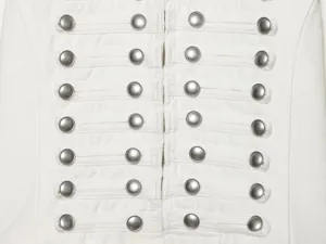 Nahaufnahme der vorderen Details einer weißen Jeansjacke mit silbernen Knöpfen und Schlaufen.