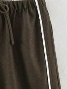 Detail shot of dark brown casual pants featuring an elastic drawstring waist and white side stripe.