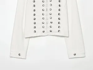 Detailansicht der weißen Jeansjacke mit auffälligen Metallknöpfen und Knotendekor.