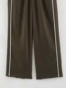 Detailed shot of women's casual trousers featuring dark brown fabric and chic white side stripes.