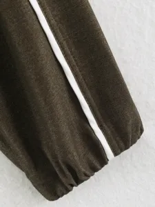 Close-up detail of women's contrast color jacket sleeve, dark brown fabric with white stripe.