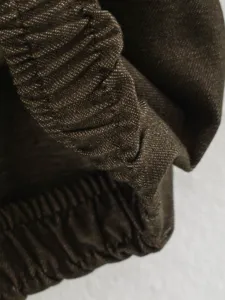 Dark brown textured fabric detail with elastic pleated design for stylish women apparel.