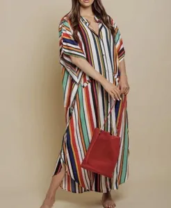 Detailed view of the colorful striped beach dress with loose sleeves and a red bag.