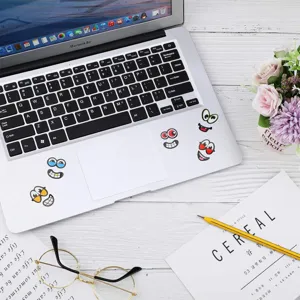 Detailed view of funny cartoon eye and mouth stickers decorating a sleek laptop surface.