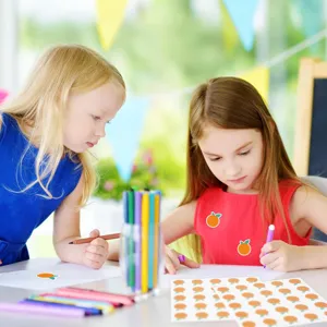 Vue détaillée montrant des enfants utilisant de mignons autocollants de fruits et des feutres.