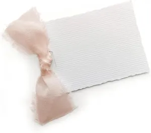 Tarjeta de sitio blanca en blanco con cinta rosa deshilachada para decoración de boda.