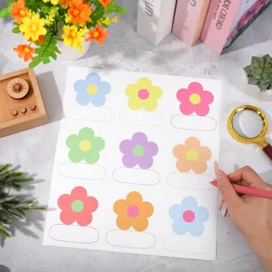 Close-up detail of colorful bohemian floral name label stickers on grey textured tabletop.