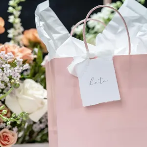 Elegante bolsa de regalo rosa con papel de seda blanco e etiqueta ideal para bodas.