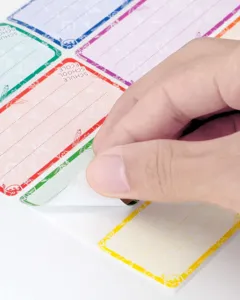 Detailaufnahme zeigt das Abziehen von selbstklebenden bunten Schulkind-Etiketten.