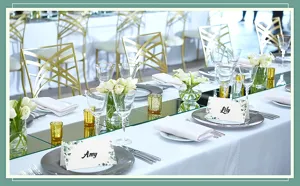 Folded wedding place cards with watercolor greenery leaves, elegant table setting party decor.