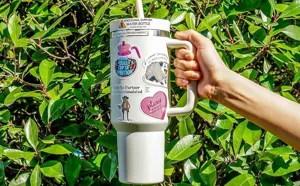 Detailansicht lustiger englischer Zitate-Aufkleber auf einem weißen Becher im Freien.