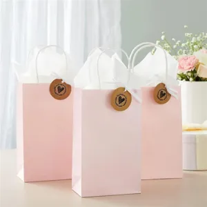 Pink paper gift bags with handles and cute heart tags for weddings and party favors.