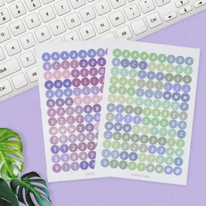 Detailed view of colorful round alphabet and number sticker sheets arranged on a desk.