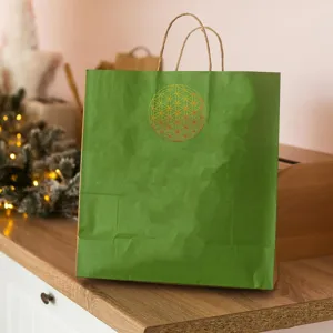 Detailed view of a green paper gift bag featuring a golden sacred geometry flower symbol.