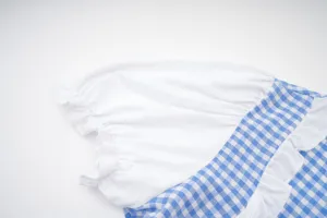 Close up view of the blue and white plaid dress featuring white puff sleeves and ruffles.