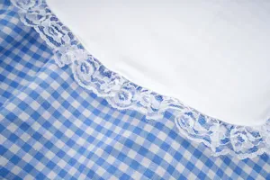 Detailed view of blue and white gingham fabric with delicate white floral lace trim.