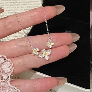 Detailaufnahme einer zarten Titanstahl Blumenkette mit drei charmanten Blütenanhängern.