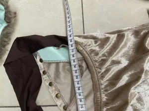 Dettaglio costume vichingo in velluto dorato, finiture marroni e rivetti metallici.