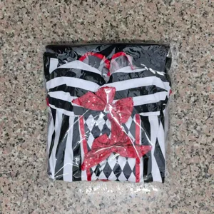 Primer plano detallado del disfraz de arlequín blanco y negro empaquetado con lazos rojos.