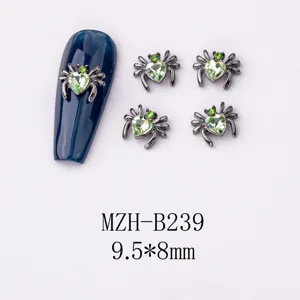 Detailansicht von dunklen Gunmetal Spinnen Nagelkunst Anhängern mit grünen Herzsteinen.
