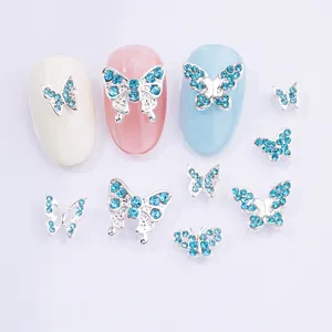 Dettaglio di unghie a farfalla in argento con strass blu chiaro brillanti per nail art.