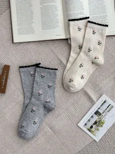 Detail flat lay of cotton mid-calf socks with sweet tulip prints and black ruffled cuffs.
