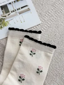 Detail view of women's floral embroidered mid-calf socks with scalloped cuffs and soft combed cotton.