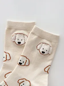 Close-up detail of beige cute puppy embroidered cotton socks, soft texture and cute animal pattern.