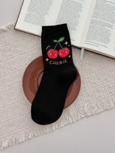 Close-up detail of cute black mid-tube socks featuring red cherry embroidery and chic lettering.