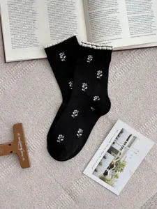 Black cotton crew socks with white tulip flower patterns and cute ruffled cuffs for women.