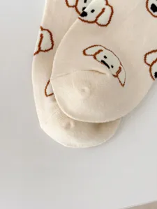 Close-up detail view of cute puppy pattern beige combed cotton socks, soft knit texture.