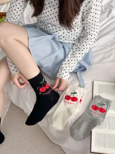 Cute cherry embroidered cotton mid-tube socks detail shot, cozy lifestyle bed setting display.