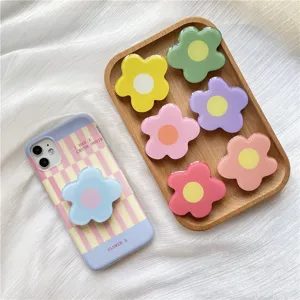 Close-up view of colorful resin flower phone grips and matching pastel case on tray.