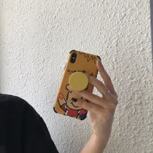 Cute cartoon bear phone case with telescopic airbag bracket and convenient desktop stand design.