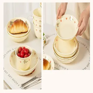 Detail shot of cute cream ceramic bowl set featuring delicate flower and heart underglaze patterns.