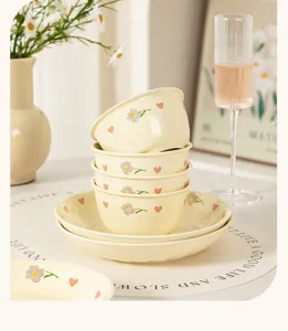 Close-up detail of cream style ceramic rice bowl and plate set with cute flower and heart pattern.
