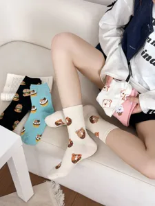 Close-up detail of cute cartoon bear and donut pattern cotton mid-tube socks for women.