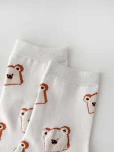 Close-up detail shot of cute flocked cartoon bear white cotton mid-tube socks for women.
