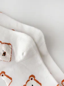 Close-up detail of white cotton socks featuring cute brown outlined bear flocking pattern.