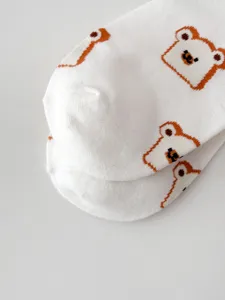 Detailed shot of white cotton socks with cute brown bear print, soft and comfortable.