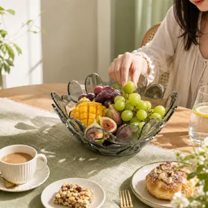 Detail shot of a grey glass petal fruit bowl filled with fresh grapes on a cozy dining table.