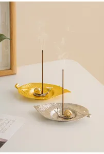Detailed view of creative leaf incense holder with cute snail, modern metal desktop decor.
