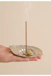 Detail shot of a creative metal leaf incense holder with a gold snail figurine for home.