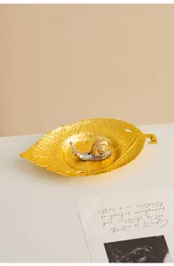 Close-up detail of the creative golden leaf dish with metallic snail incense holder tray setup.