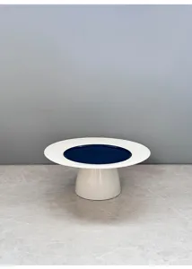Modern minimalist ceramic cake stand detail, featuring a white ray rim, blue center and pedestal.