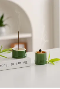 Vista dettagliata del bruciatore di incenso in ceramica di bambù verde su scrivania con fumo.