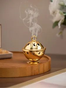 Close-up of golden metal incense burner with star and moon cutout design and rising smoke.