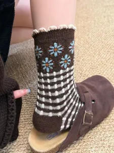 Close-up detail of women's vintage wool knit socks with blue daisy and plaid pattern.